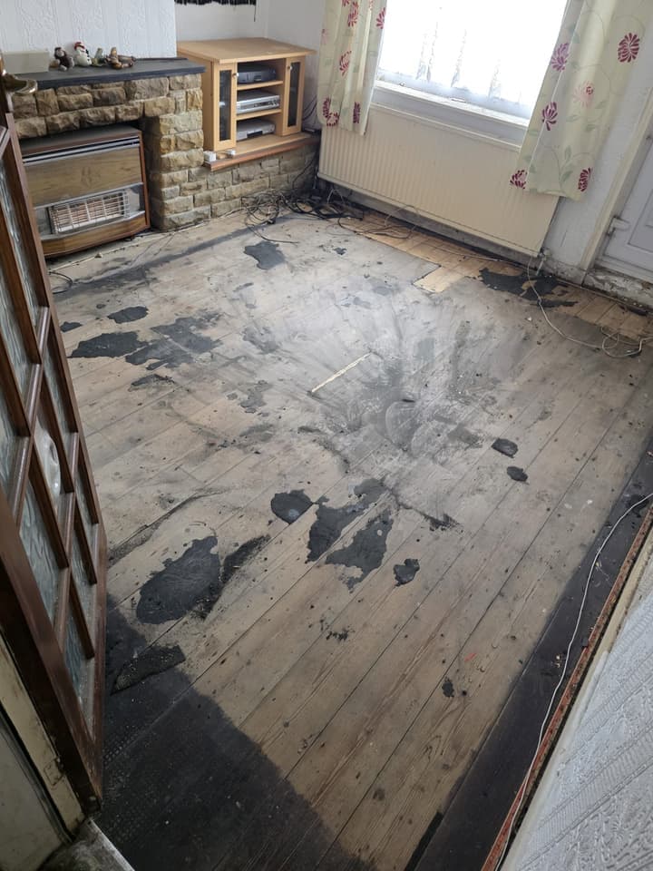 The front room after the clearance: bare floorboards, a stone fireplace and the window
