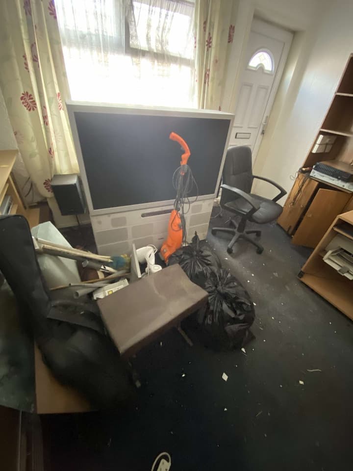 Front room before the clearance: a large television, an office chair and bags on the floor
