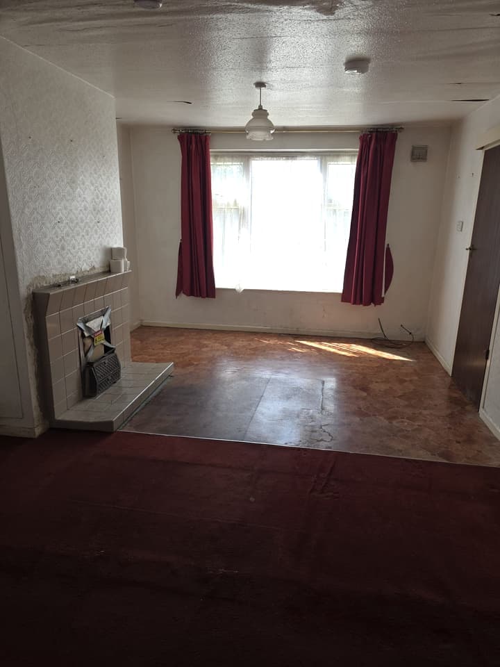 The living room after the clearance: empty, with red curtains and sunlight on the floor