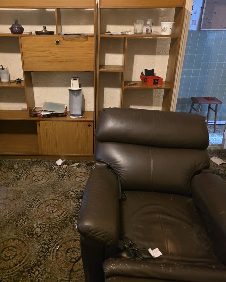 A wooden shelving unit and a leather armchair in a living room